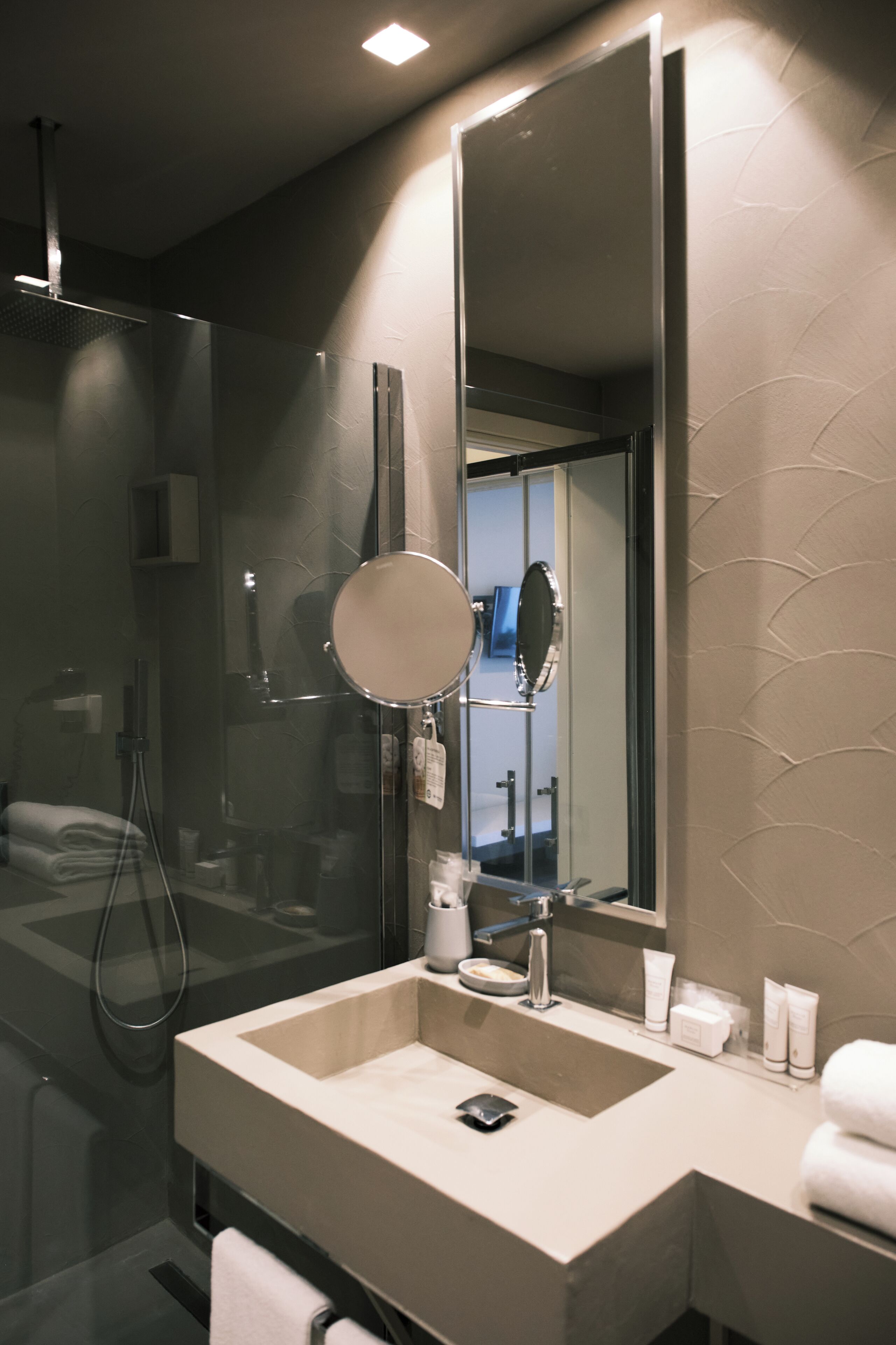 A modern bathroom with a large mirror, a sink, and a shower.