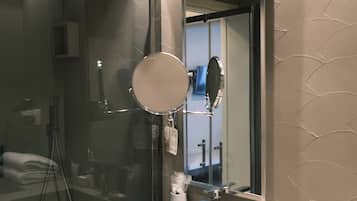 A modern bathroom with a large mirror, a sink, and a shower.
