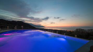 Una piscina con vistas al atardecer y montañas al fondo.