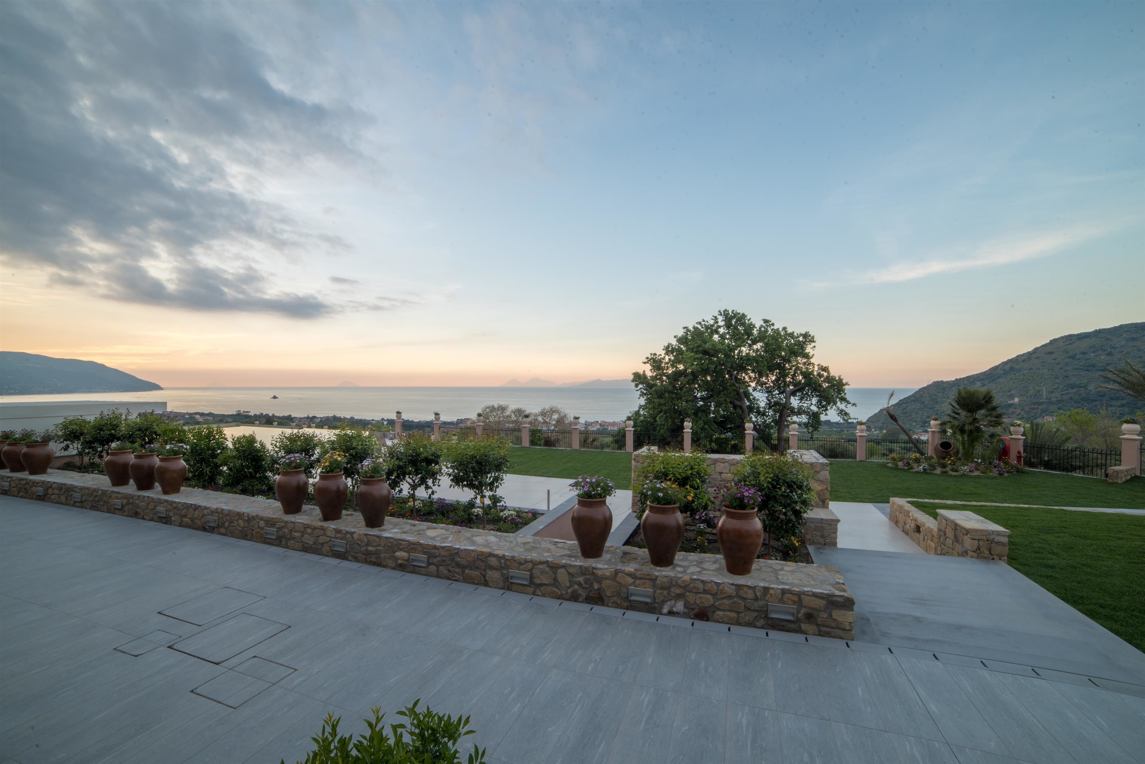 Una terrazza con fioriere in pietra e vista su un corso d'acqua e delle colline.