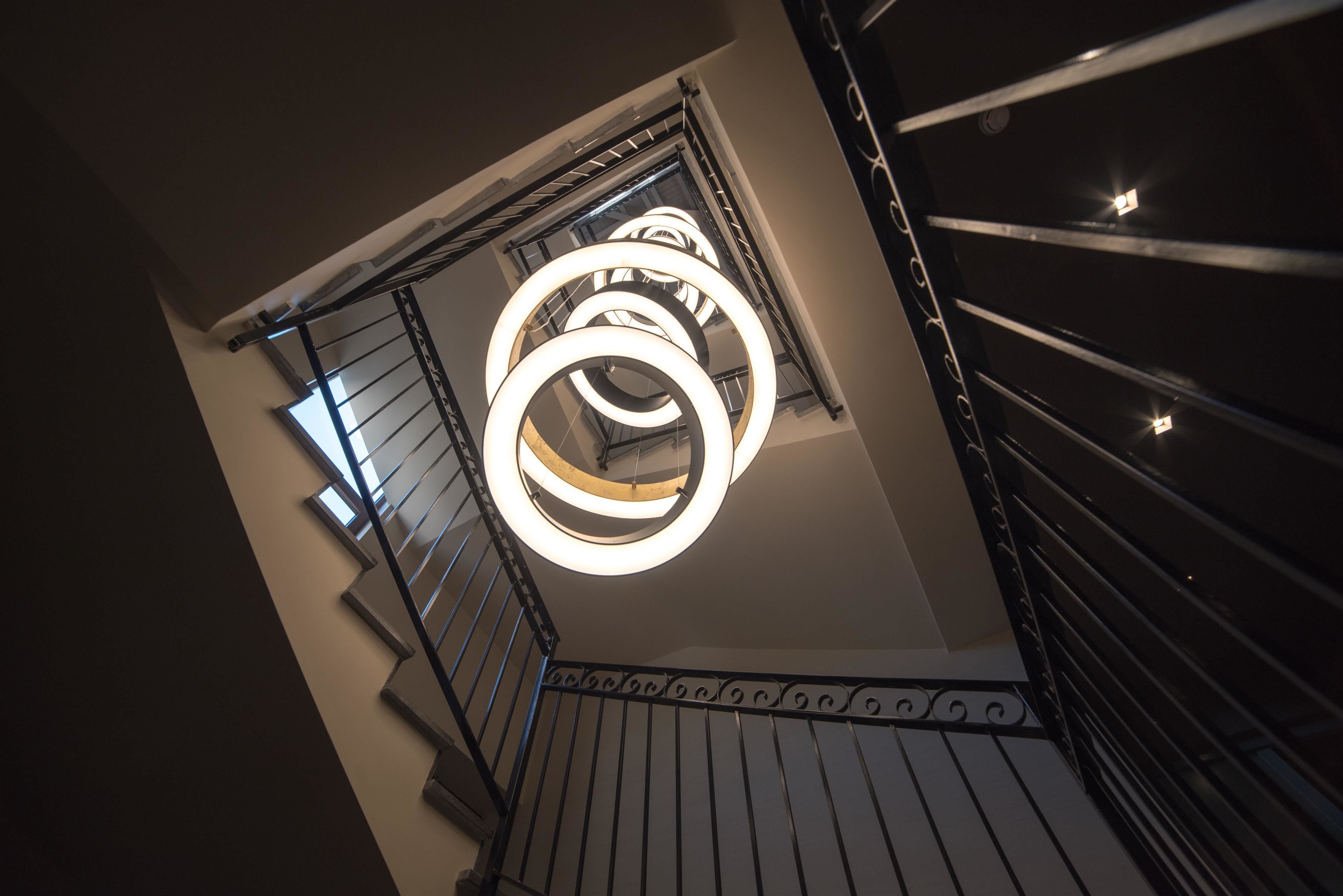 Una escalera de caracol con diseño moderno, que presenta una lámpara circular en la parte superior.