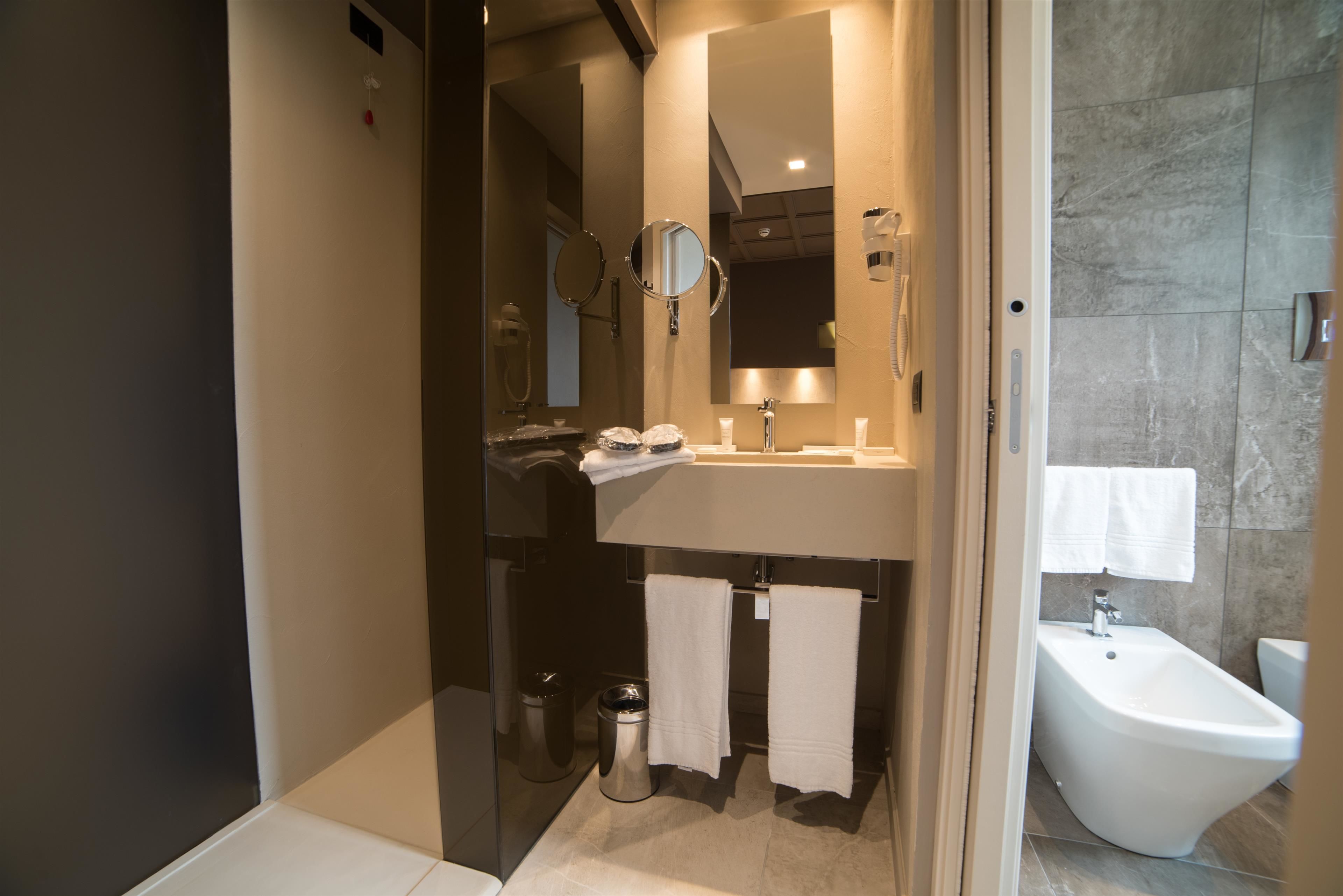A modern bathroom with a glass-enclosed shower, a sink with a mirror, and a bidet.