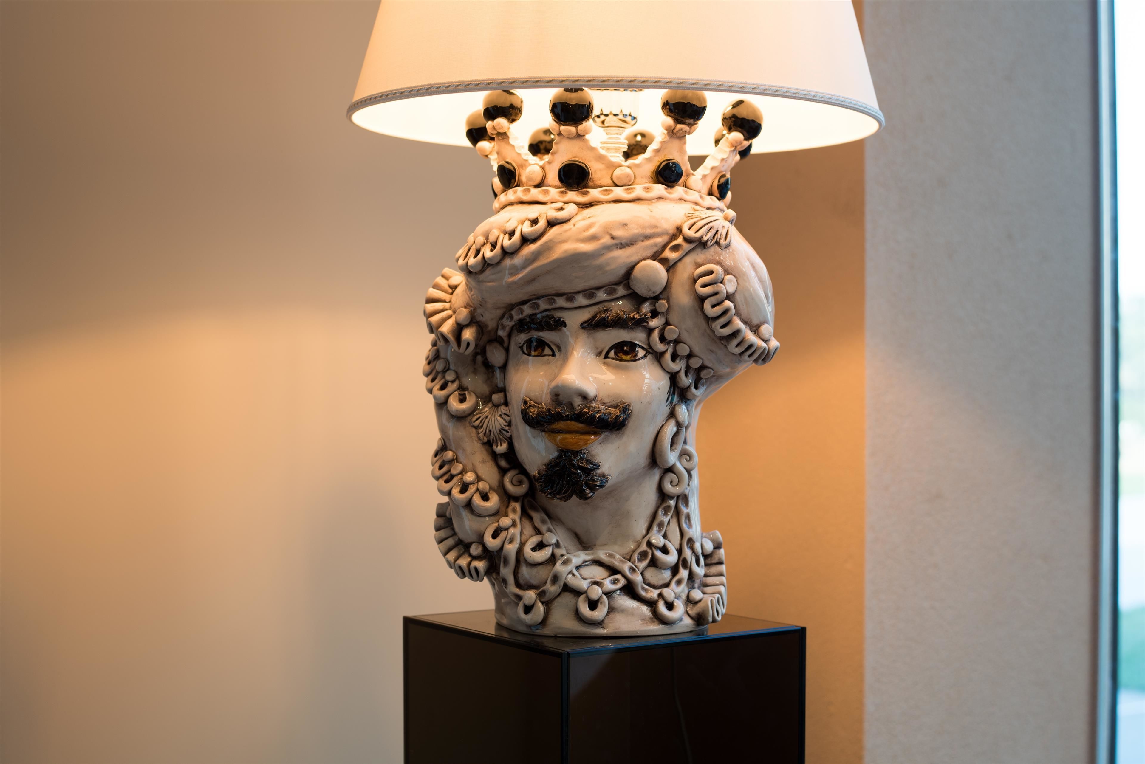 Eine dekorative Lampe mit einer kronenartigen Spitze und einem Gesicht am Sockel.