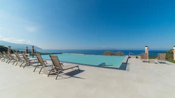 A poolside area with lounge chairs and a view of the ocean.