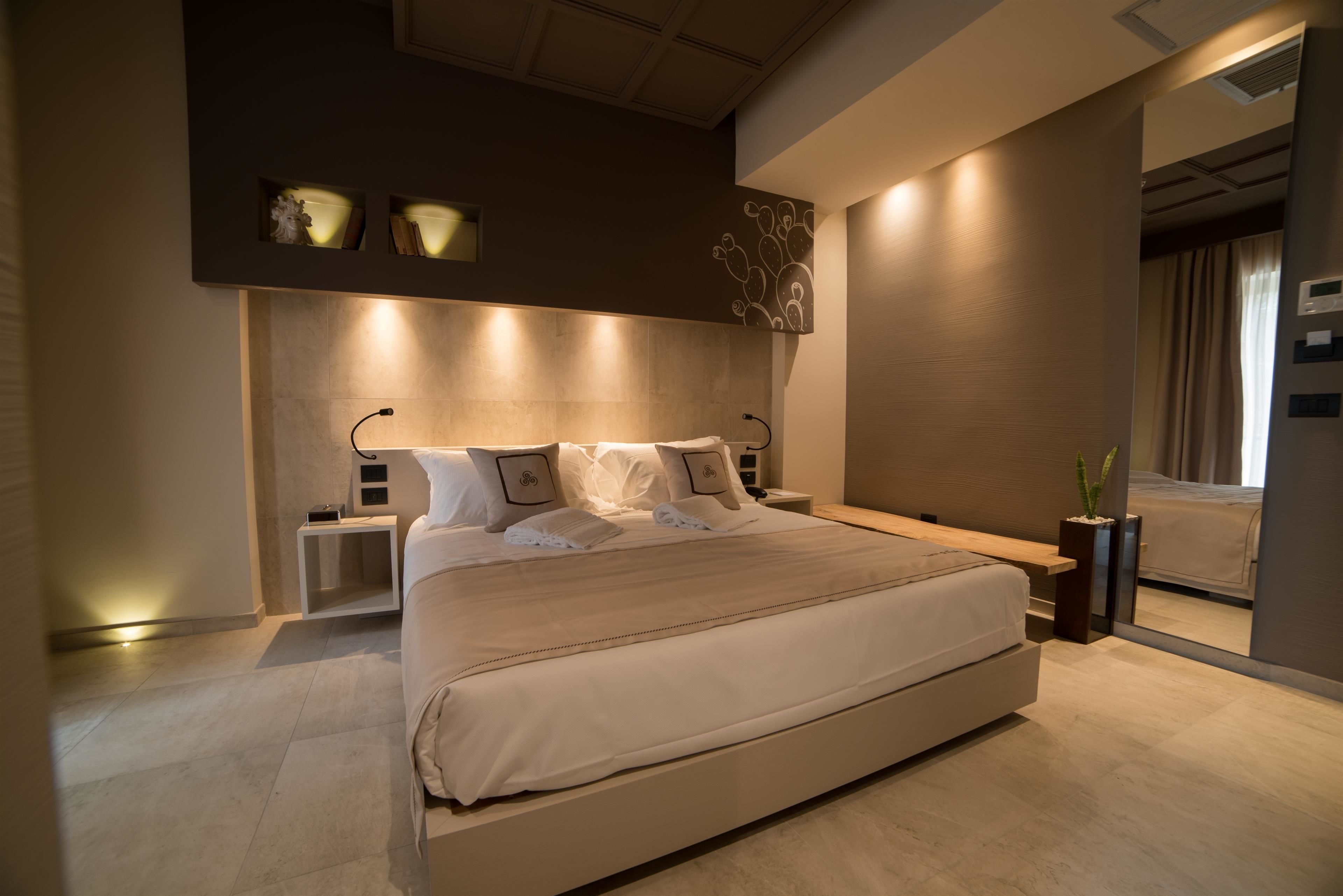 A modern bedroom with a large bed, bedside tables, and a wall-mounted light fixture.