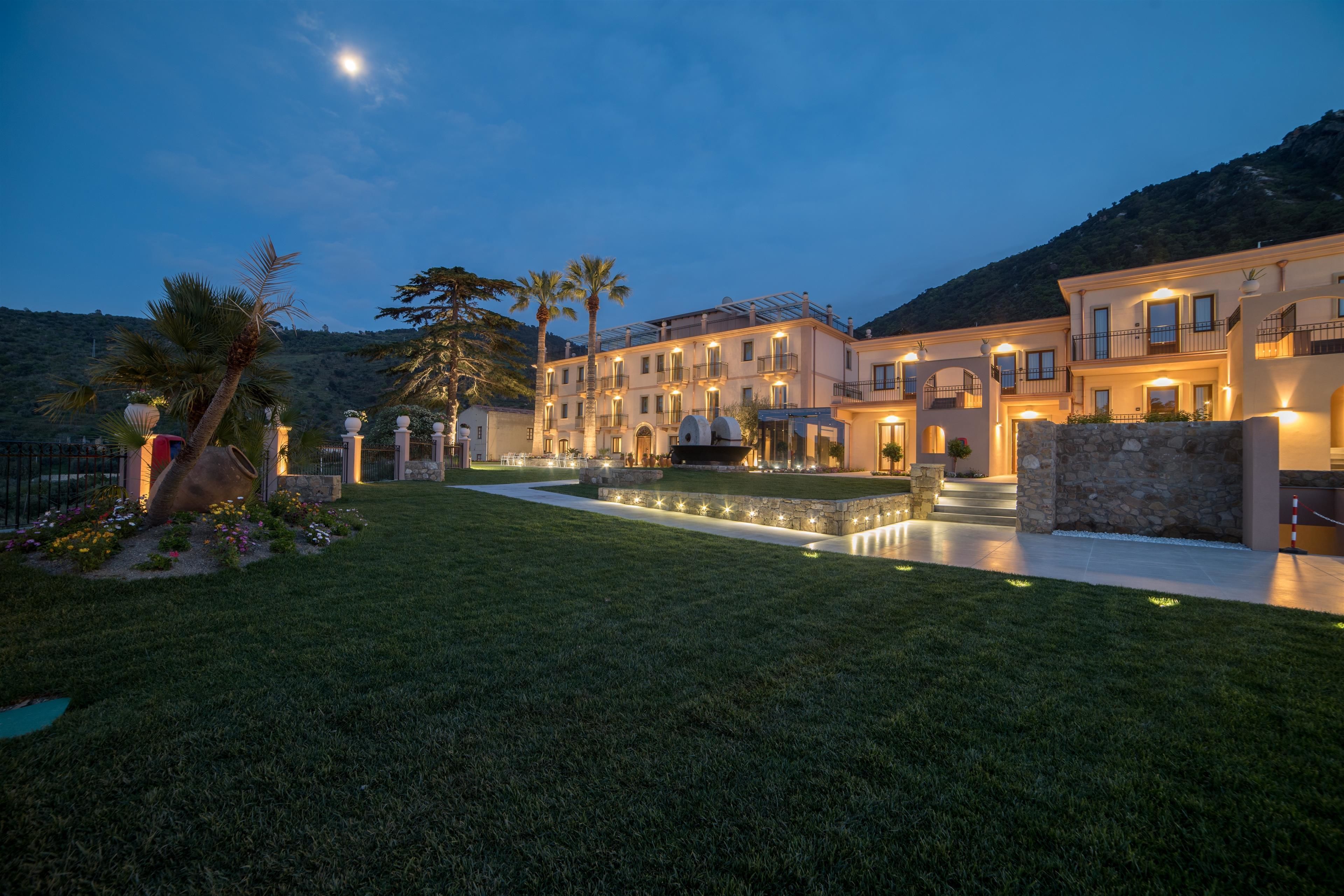 A multi-story hotel with a well-maintained lawn and a pool area.