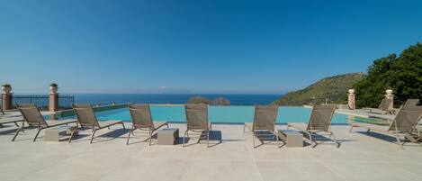 A poolside area with lounge chairs and a view of the ocean.