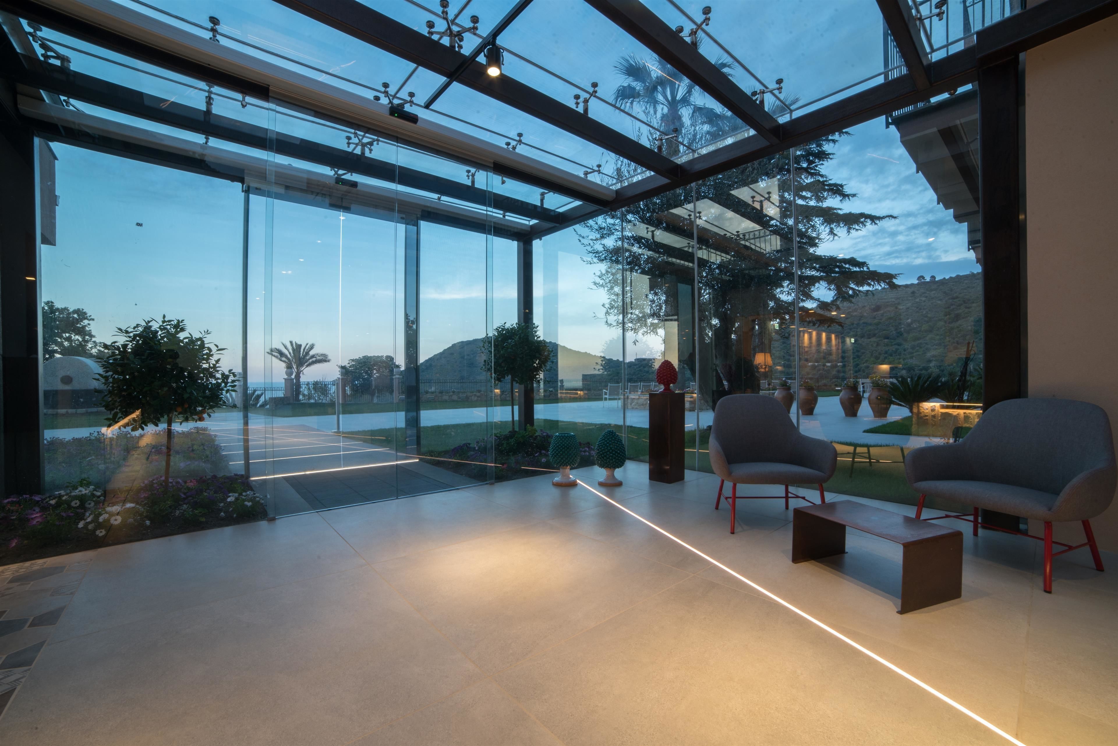 A modern interior with a glass ceiling, seating area, and a view of the outdoors.