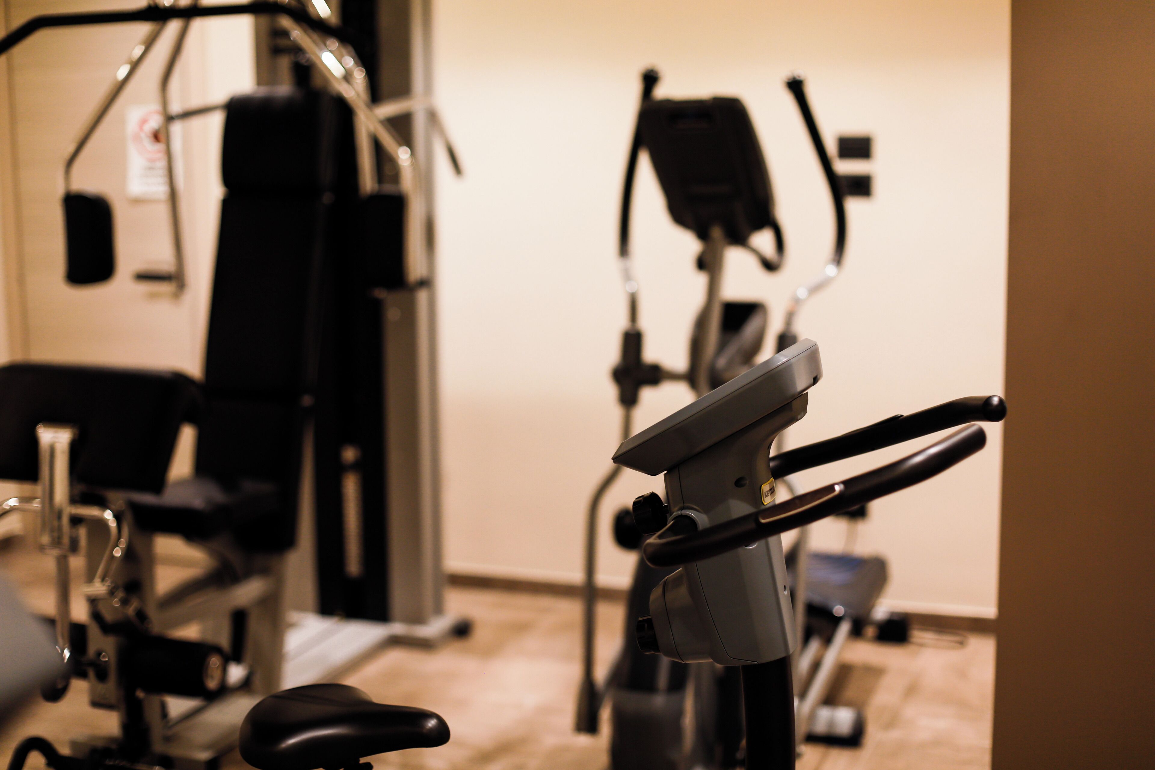 Et fitnessrum med træningsudstyr, herunder en motionscykel og en romaskine.