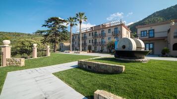 Un patio de hotel con una fuente central, muros de piedra y un sendero adoquinado.