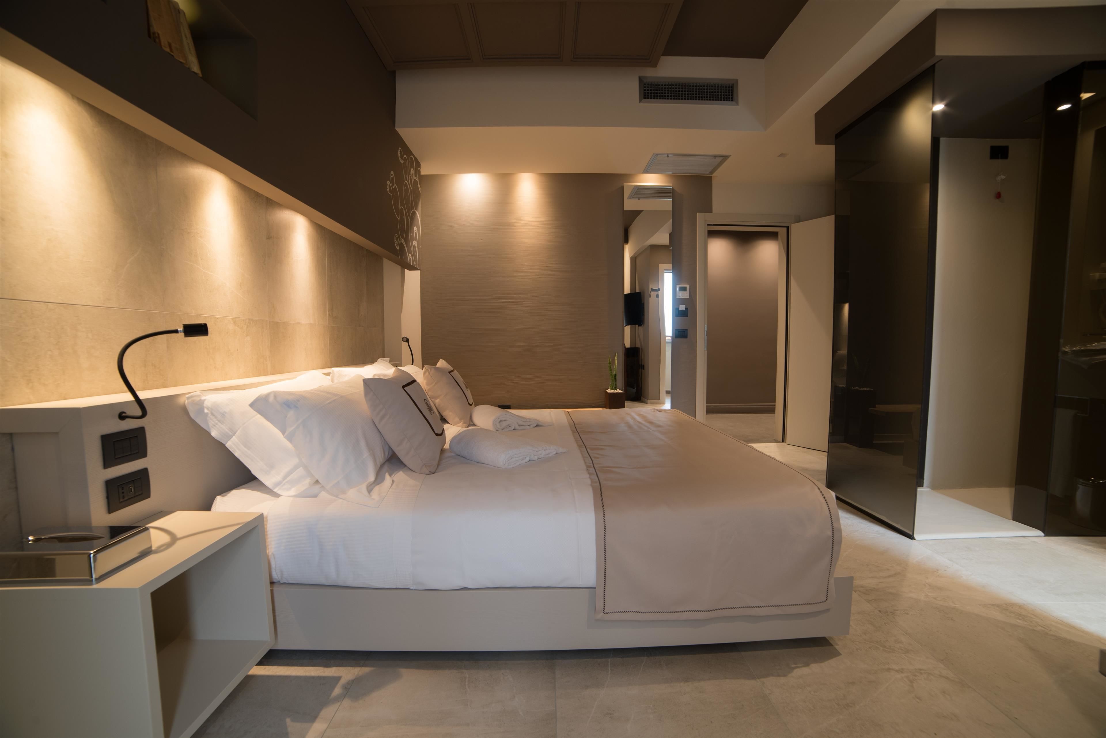 Quarto moderno com cama grande, mesas de cabeceira e televisão de tela plana.