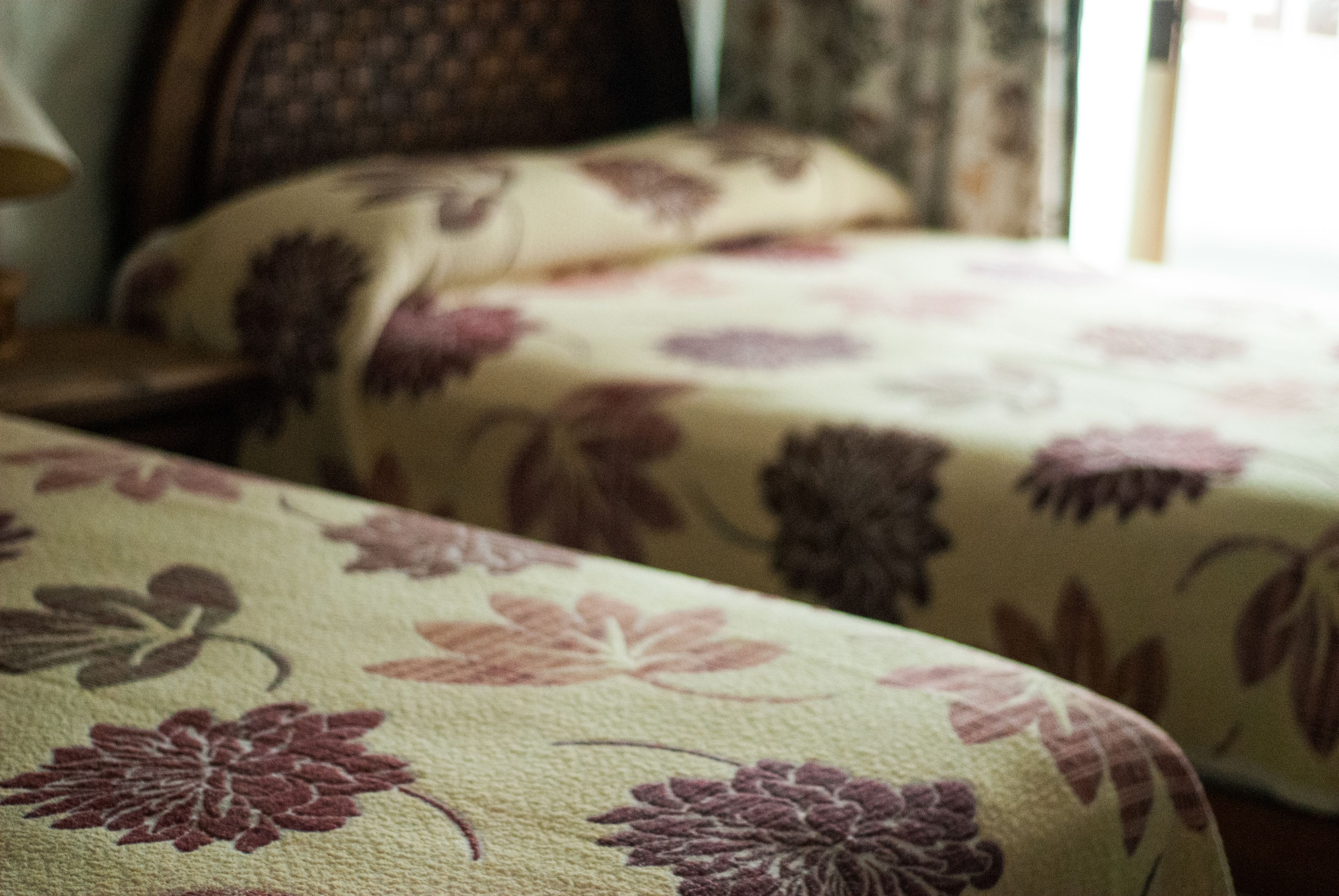 Un letto con biancheria da letto a fiori e una testiera.