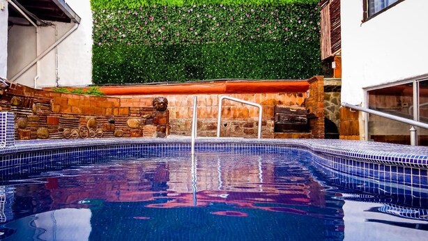 A swimming pool with a stone wall and a metal ladder.
