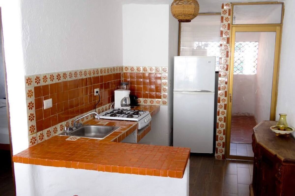 A compact kitchen with a gas stove, sink, and white refrigerator.