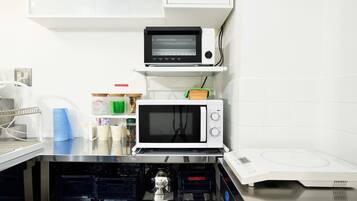 A kitchen with a microwave, toaster, and a water dispenser.