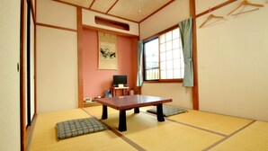 A traditional Japanese room with tatami flooring, a low table, a desk with a computer, and a window with curtains. - Oyado Nozawa (Takayama)