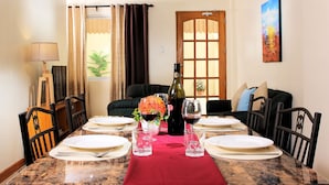 Comedor con una mesa dispuesta para seis personas, una botella de vino y un florero con flores.