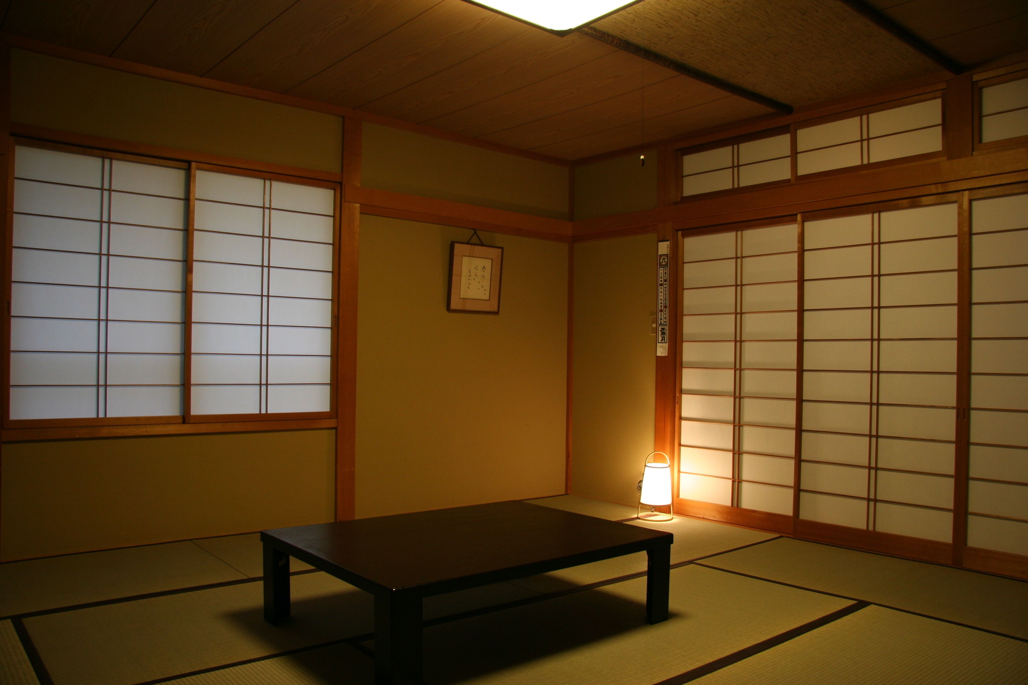 Um quarto japonês tradicional com tatames, portas deslizantes shoji e uma mesa baixa.