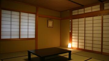 Um quarto japonês tradicional com tatames, portas deslizantes shoji e uma mesa baixa.