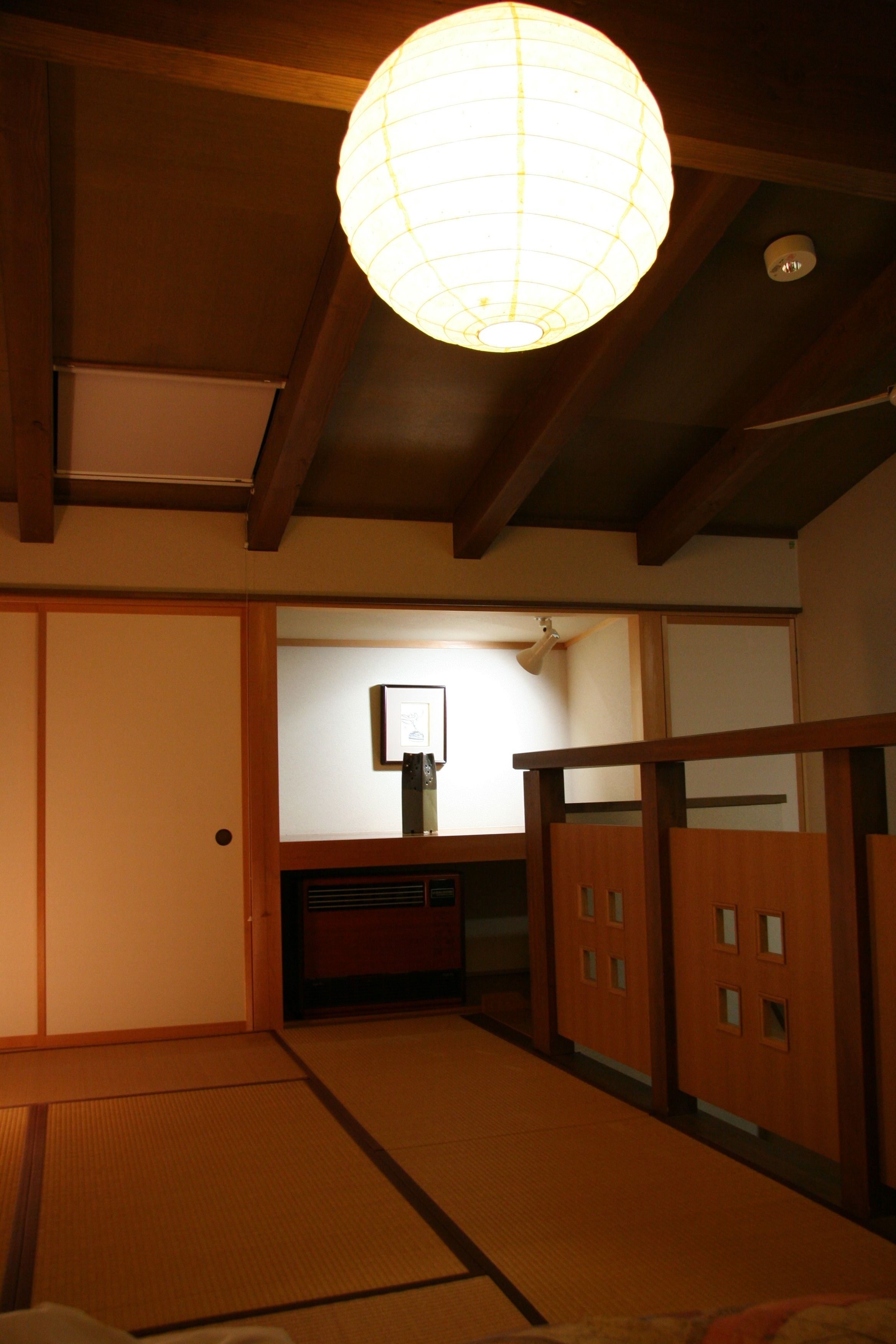 A traditional Japanese room with tatami flooring, sliding doors, and a hanging paper lantern.