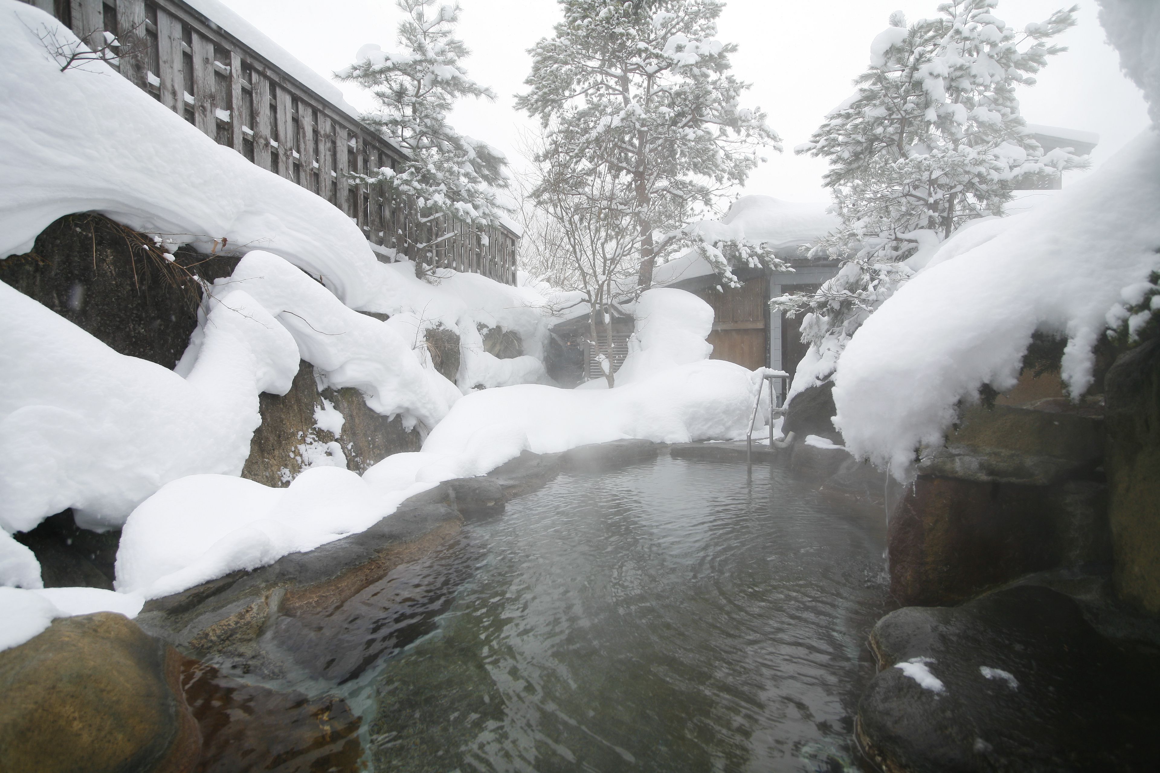 A snow-covered outdoor area with a stone structure and a clear water feature.