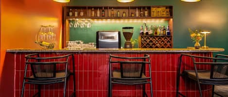 A bar area with red tiled walls, black bar stools, and overhead lighting.