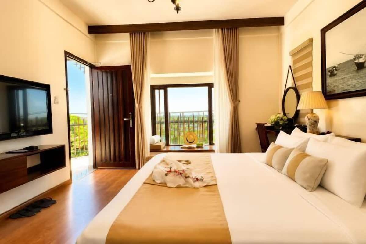 Habitación de hotel con cama, televisión y balcón con vistas.