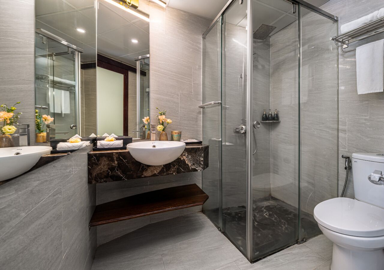 A modern bathroom with a glass-enclosed shower, a white sink, and a toilet.