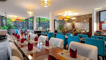 A restaurant with long communal tables, blue chairs, and red napkins.