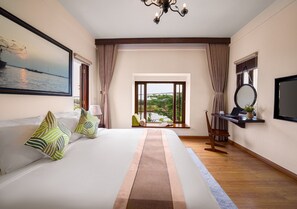 Habitación de hotel con una cama grande, vistas al exterior, un escritorio con una computadora portátil y un televisor.