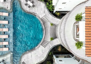 A rooftop swimming pool with a curved design, surrounded by a stone deck and a few lounge chairs. - Faifo Boutique Hotel & Spa (Da Nang)