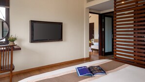Habitación de hotel con televisor de pantalla plana montado en la pared, una cama con alfombra a rayas y un panel de madera.