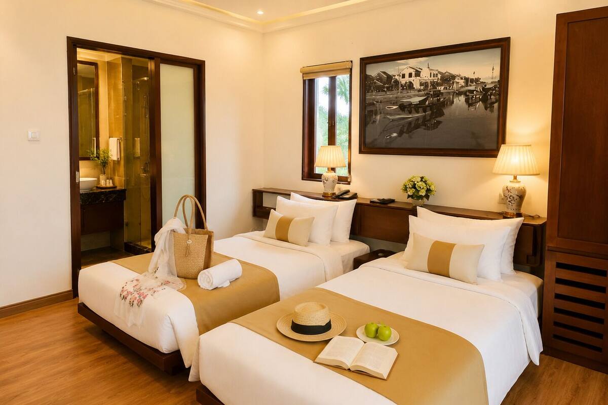 Habitación de hotel con dos camas, baño, un cuadro y suelo de madera.