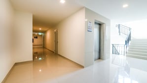 Un hall spacieux et bien éclairé, doté d’un plancher ciré, d’un escalier et d’une porte portant un numéro.