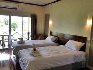 A hotel room with two beds, a wooden headboard, and a balcony with a table and chairs. - Be Fine Sabuy Hotel & Resort (Surat Thani)