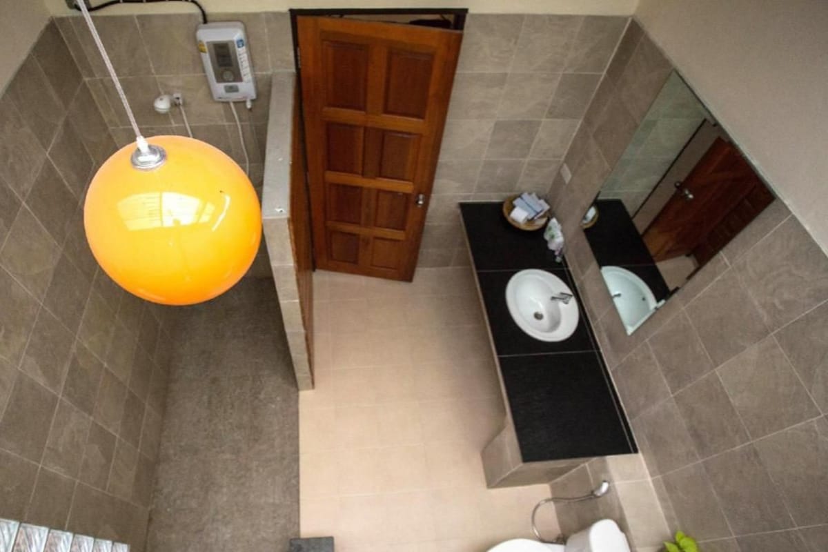 Ein Badezimmer mit Toilette, zwei Waschbecken, einem Spiegel und einer Deckenleuchte.