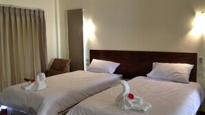 Een hotelkamer met twee bedden, elk met witte lakens en een decoratieve handdoek in de vorm van een zwaan.
