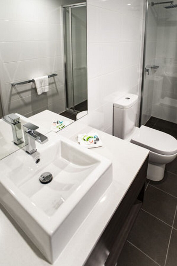 A modern bathroom with a white sink, mirror, and toilet.