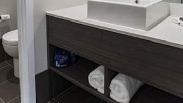 Ein modernes Badezimmer mit einem weißen Waschbecken, einem dunklen Holz-Schränkchen und einem großen Spiegel.