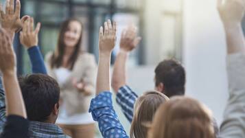 Um grupo de pessoas levantando as mãos durante uma reunião ou discussão.