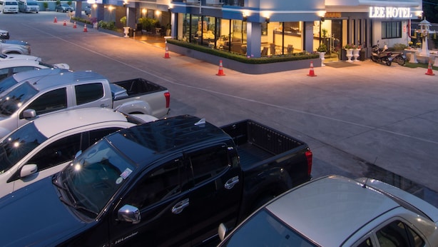 A multi-story hotel with a modern design, featuring balconies and a parking lot with several vehicles. - Lee Hotel (Surat Thani)