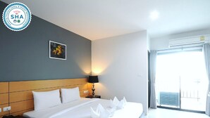 A hotel room with a bed, bedside table, lamp, and a wall-mounted picture. - Lee Hotel (Surat Thani)