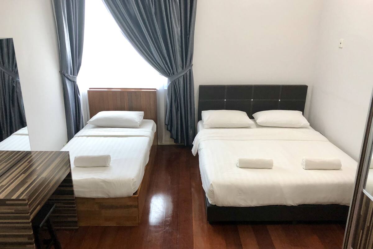 Habitación de hotel con dos camas, suelo de madera y una mesa de madera.