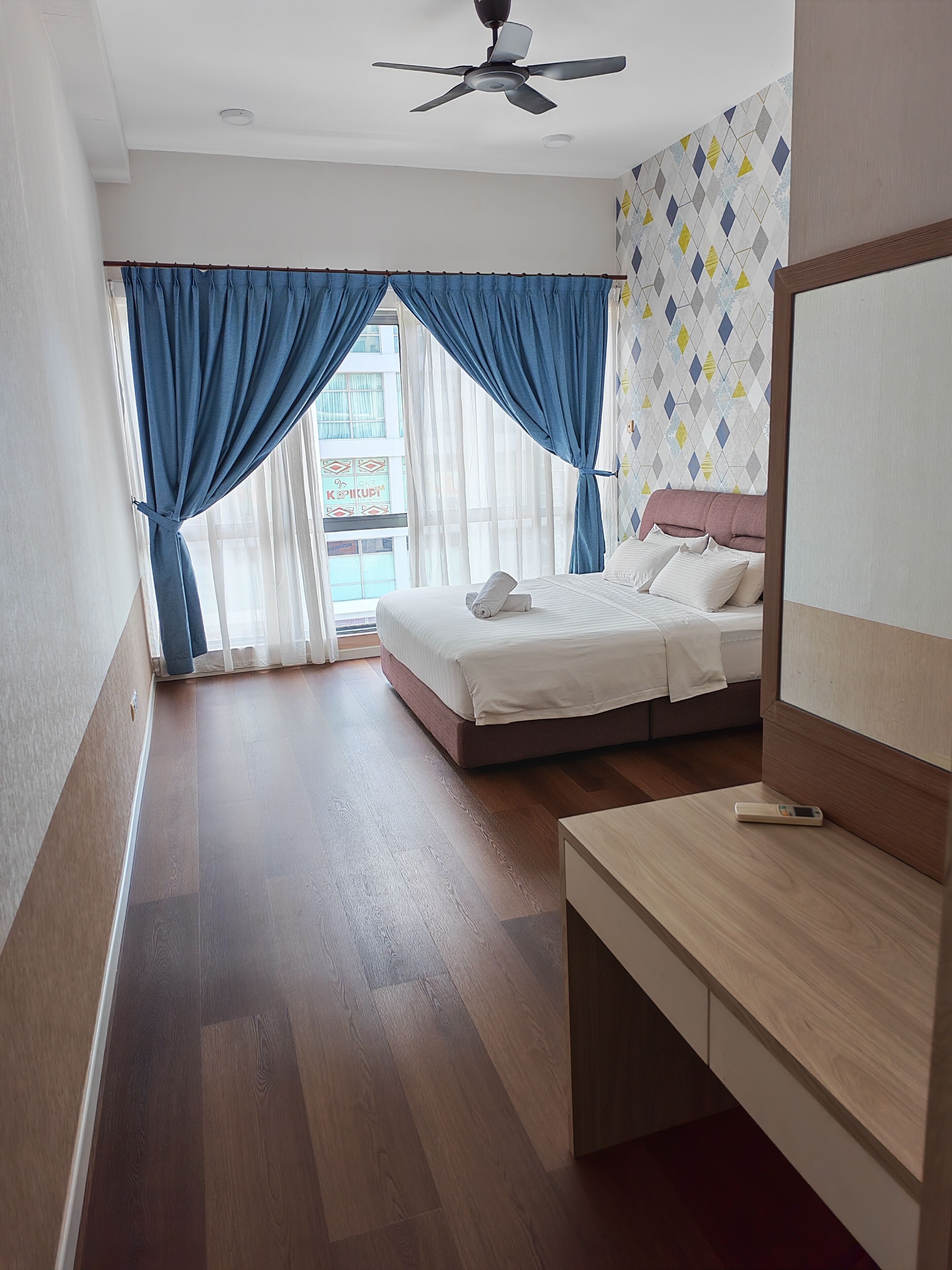 Habitación de hotel con cama, escritorio y ventilador de techo.