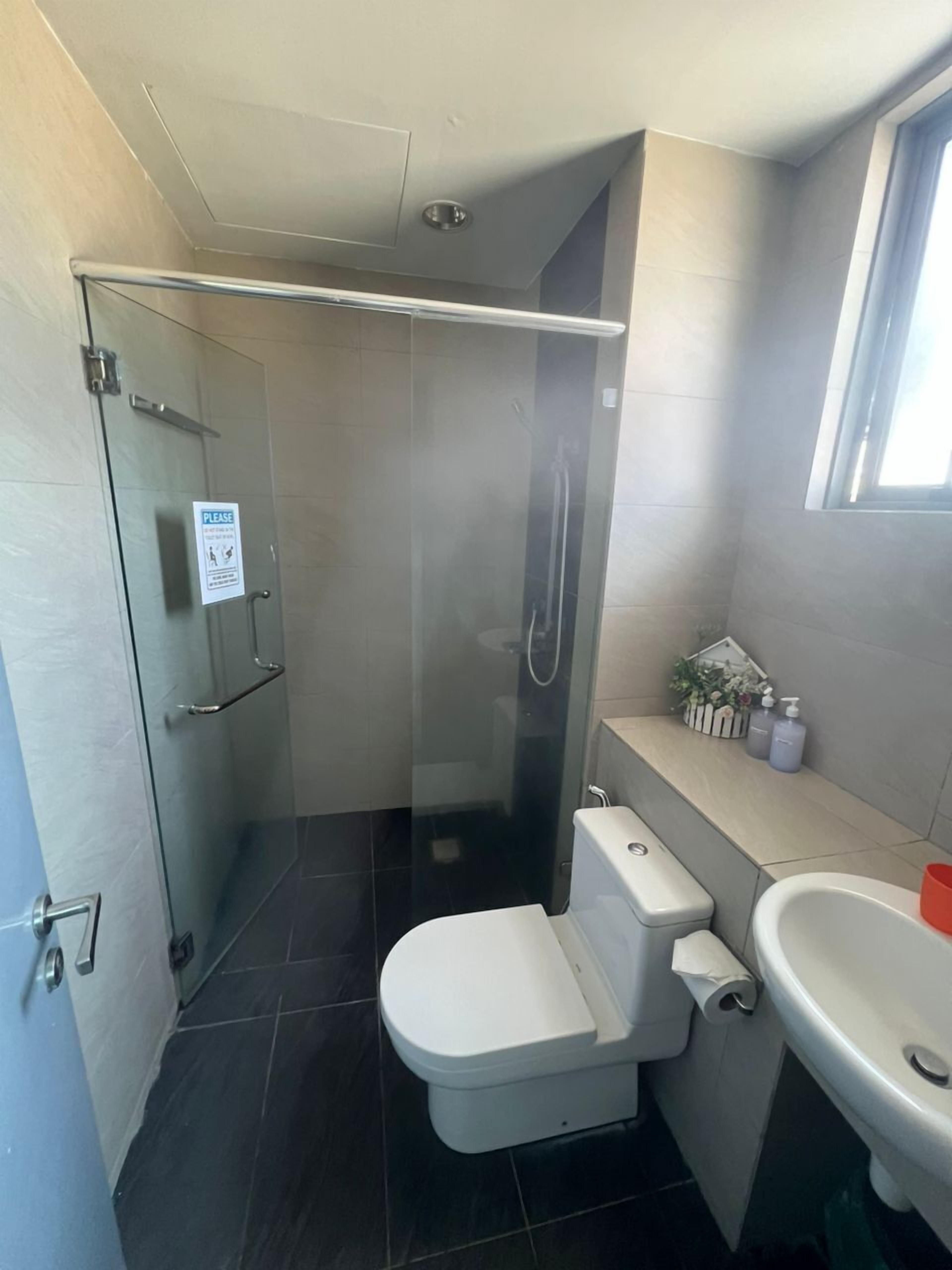A modern bathroom with a glass-enclosed shower, a toilet, and a sink.