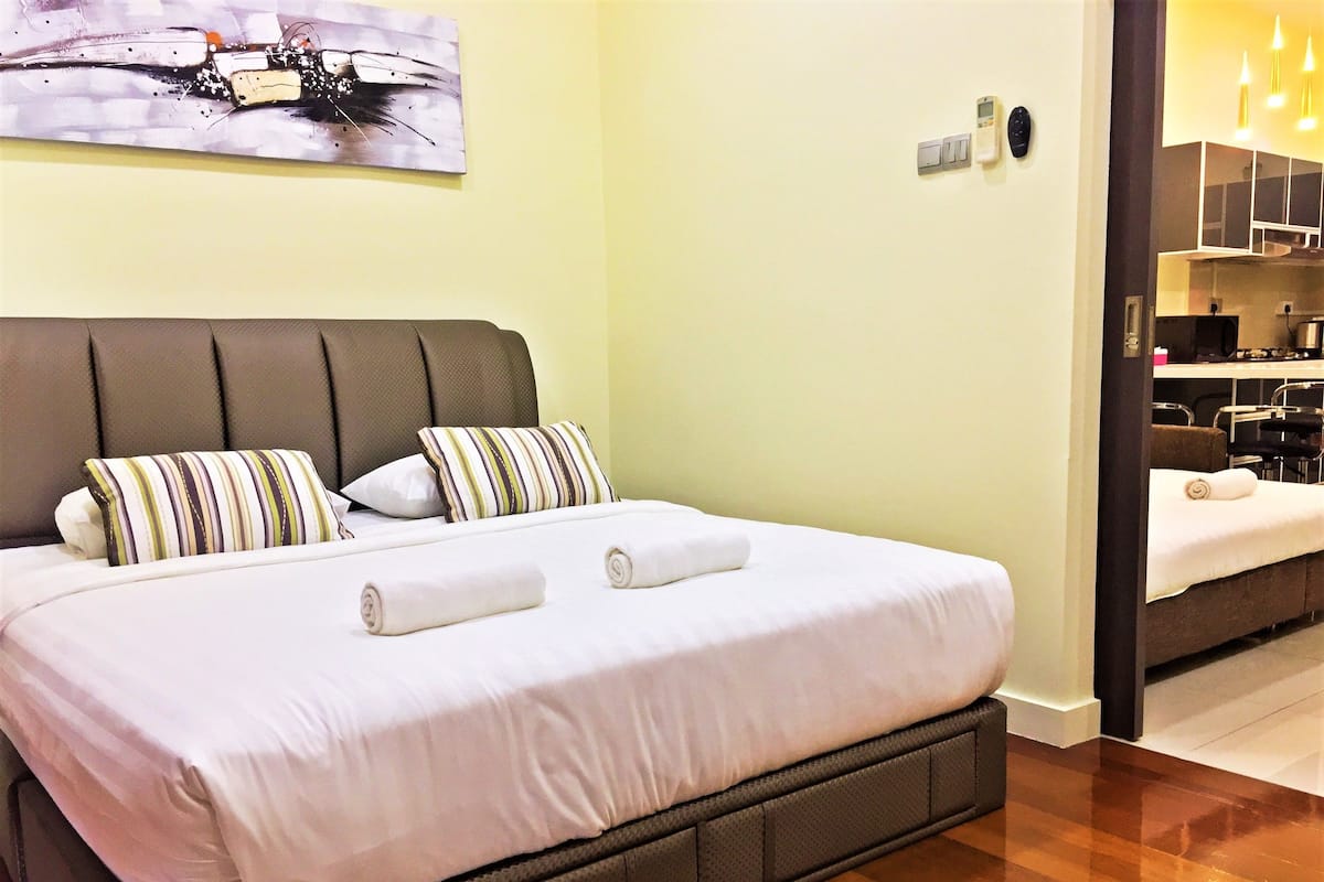 Habitación de hotel con una cama grande, cabecero, dos almohadas, una manta y un cuadro en la pared.