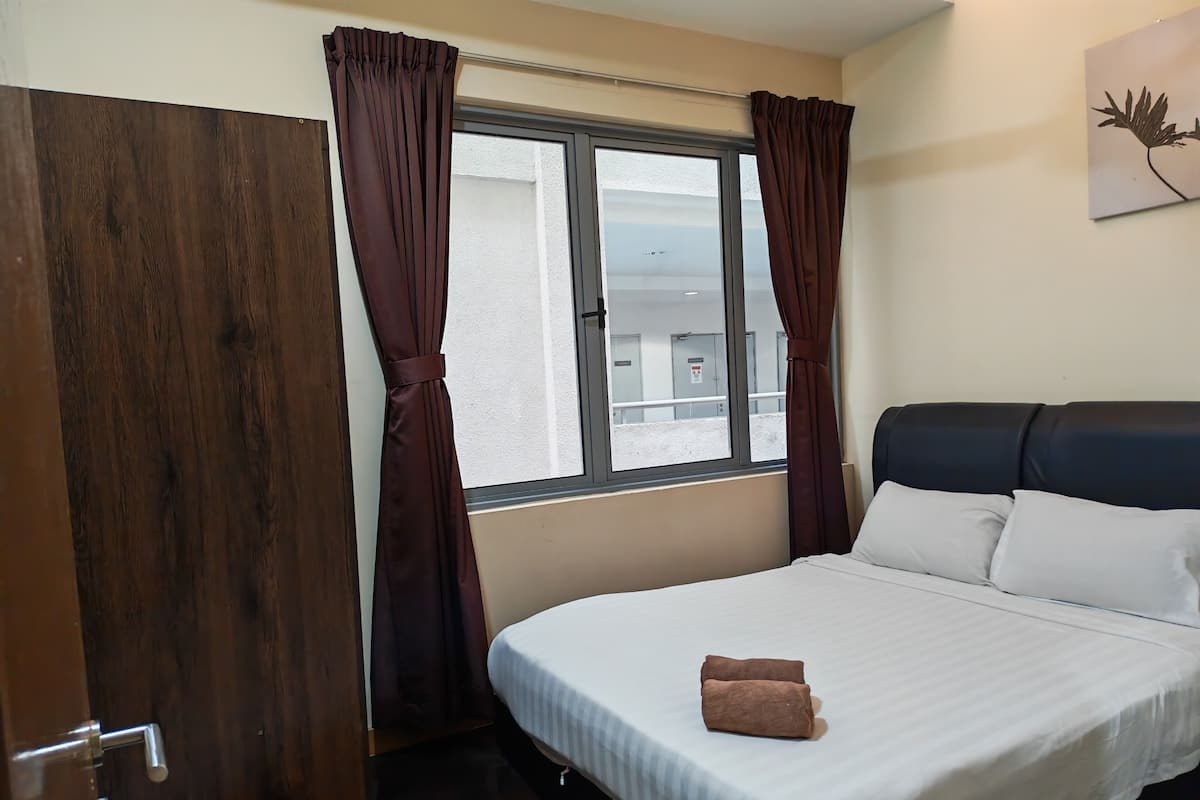Una habitación de hotel con cama, ventana con cortinas, puerta y una obra de arte colgada en la pared.