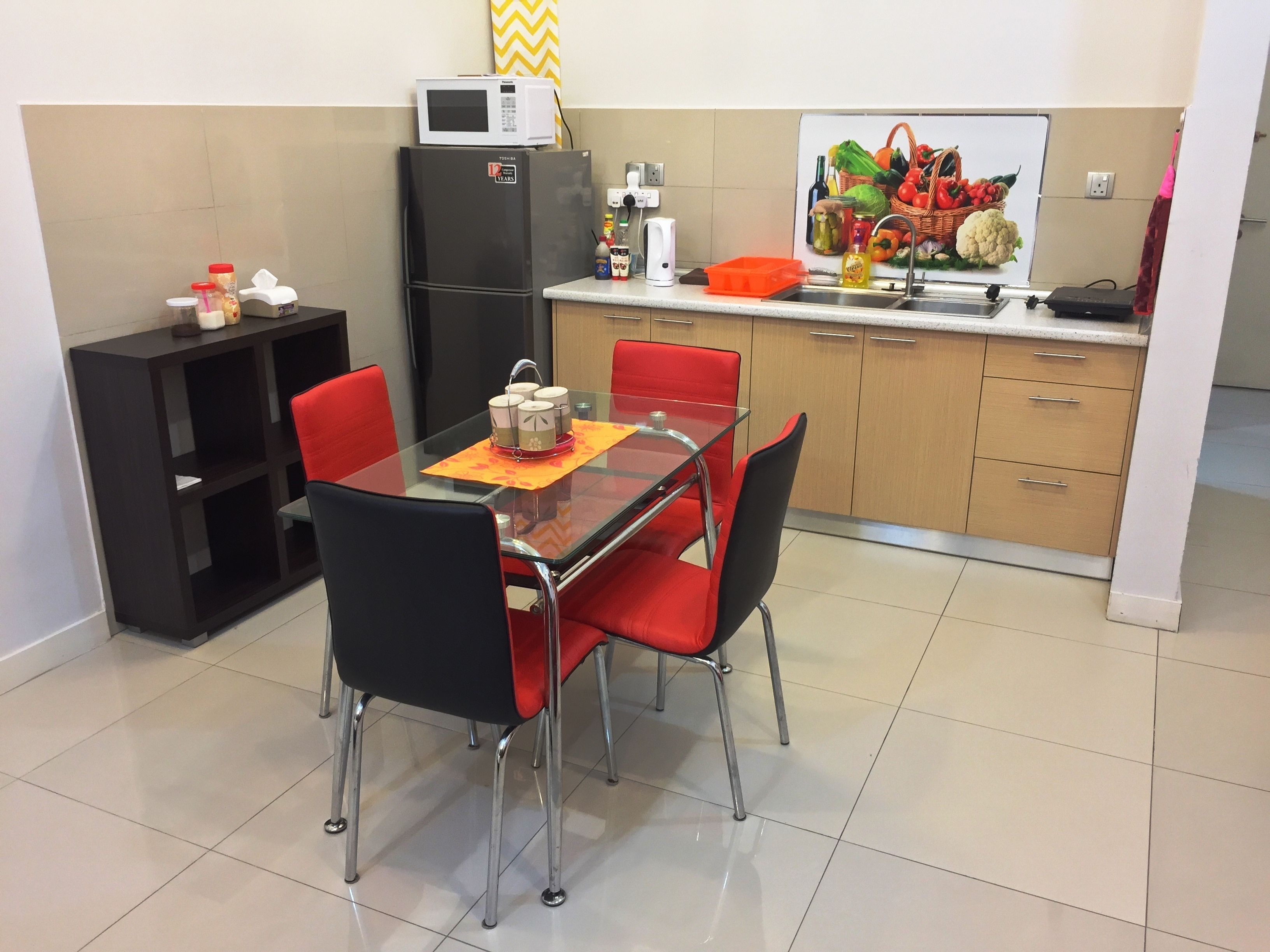 A compact kitchen with a dining area, featuring a microwave, refrigerator, and a variety of kitchen appliances.