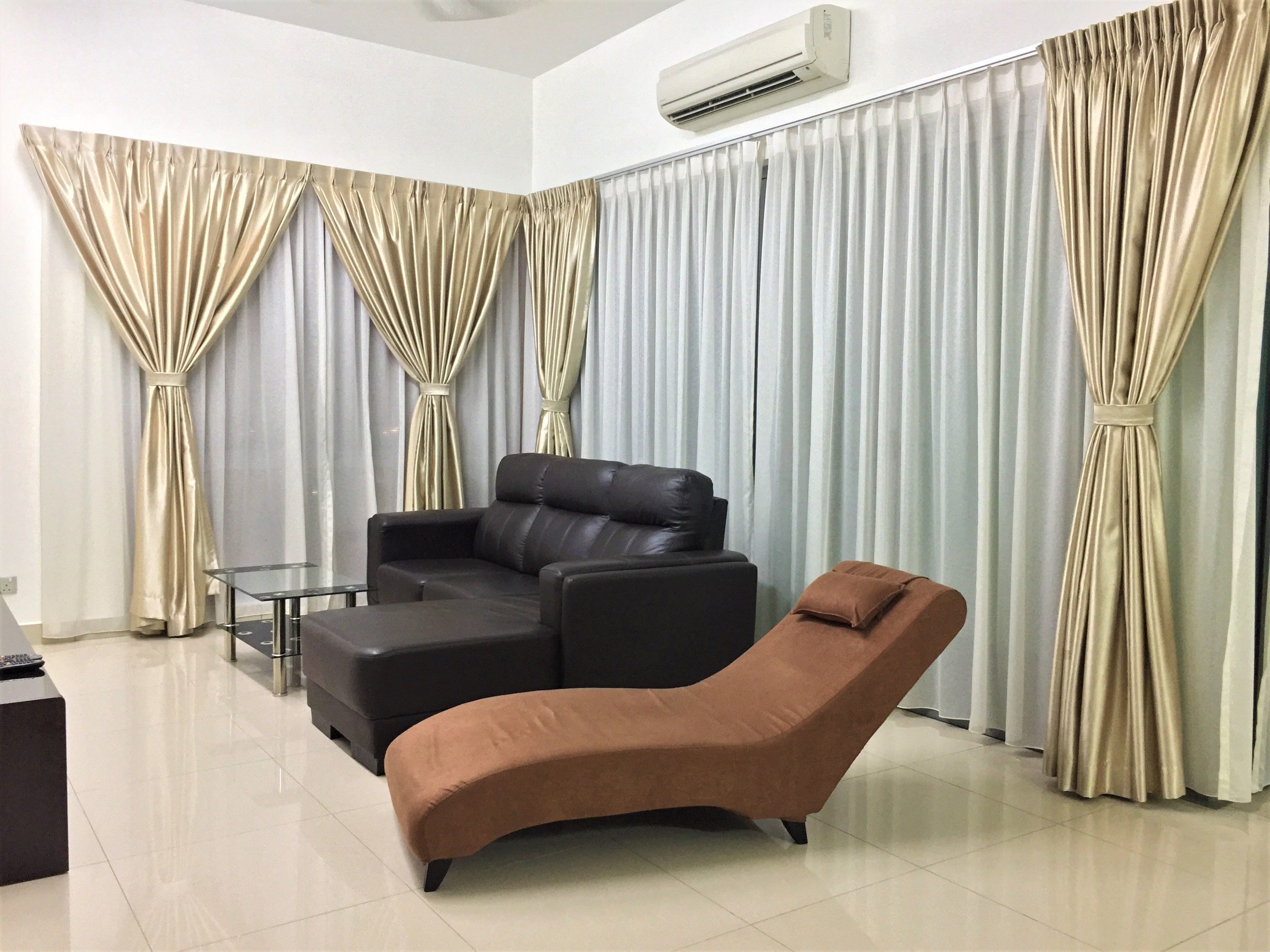 A modern living room with a black leather sofa, a brown lounge chair, and a small side table.
