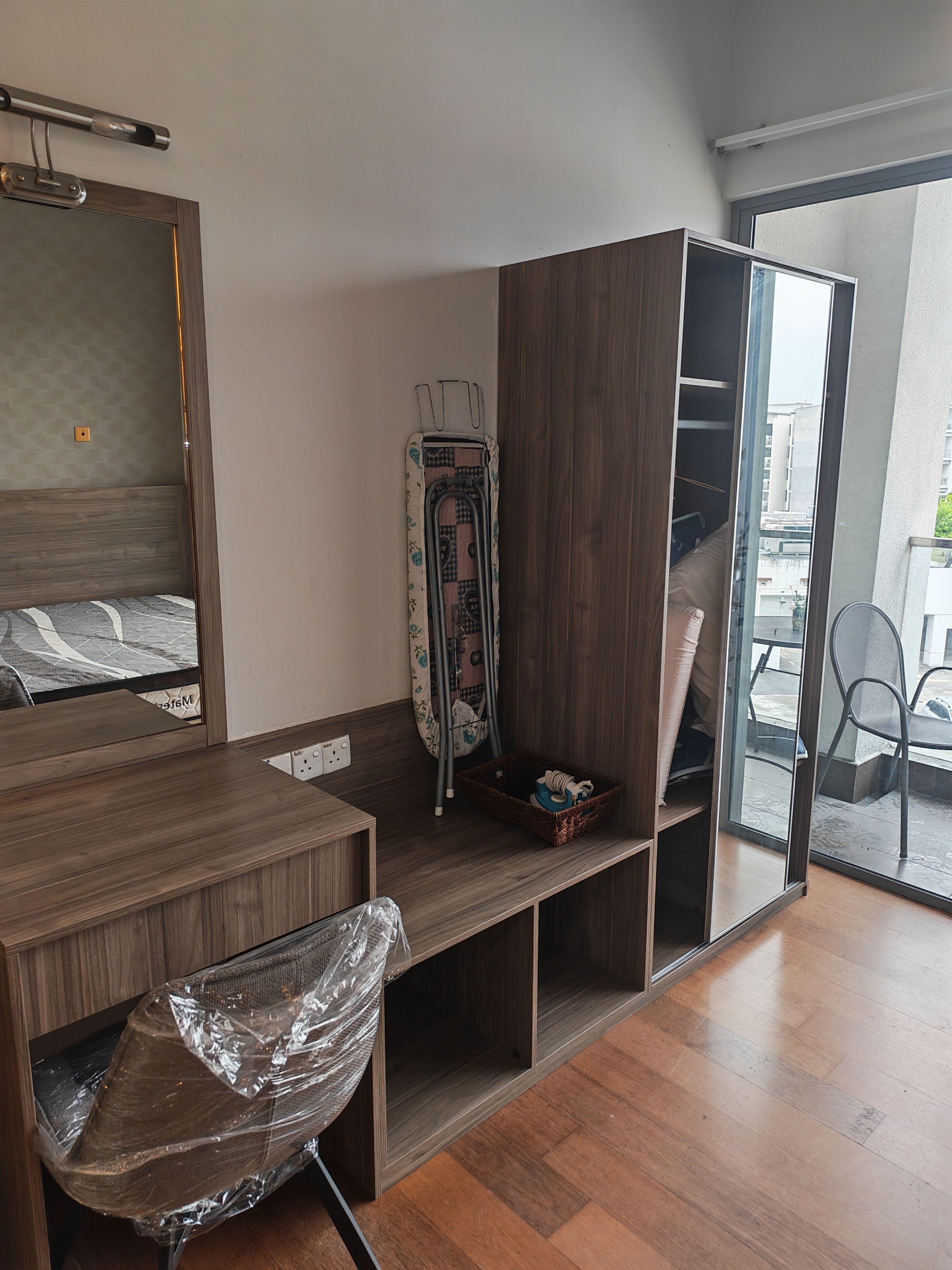 A room with a wooden desk, a chair, a wardrobe, and a large mirror.